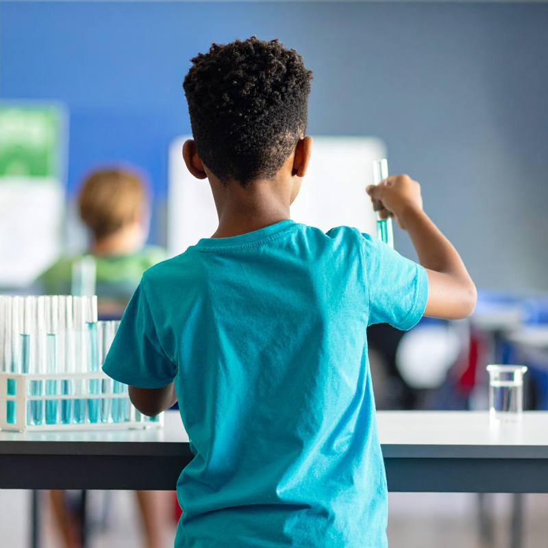 Schoolchild from behind with test tube